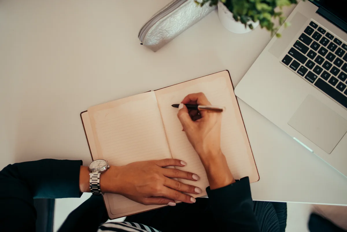 Profissional de redação estratégica planejando a estrutura editorial e o briefing de um artigo em notebook e caderno